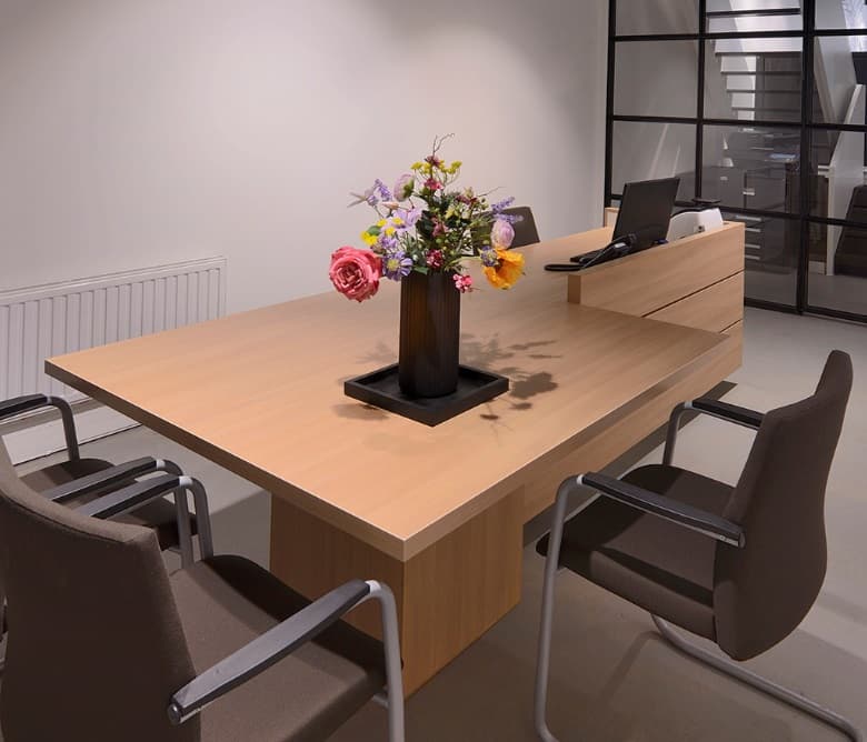 Maatwerk vergadertafel in eiken bij een stalen wand met glas