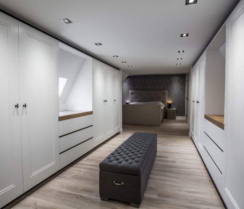 Langgerekte dressing in wit lakwerk met lades en een zitbank, in de gang naar de slaapkamer