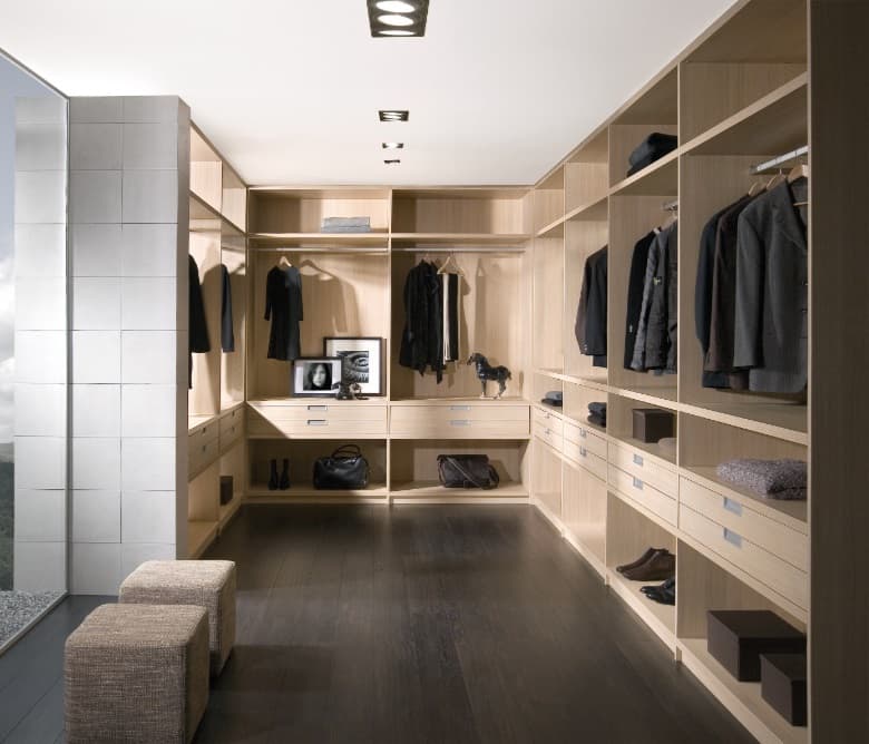 Dressing in licht eiken langs twee wanden, met hangroedes, open vakken en een donkere vloer
