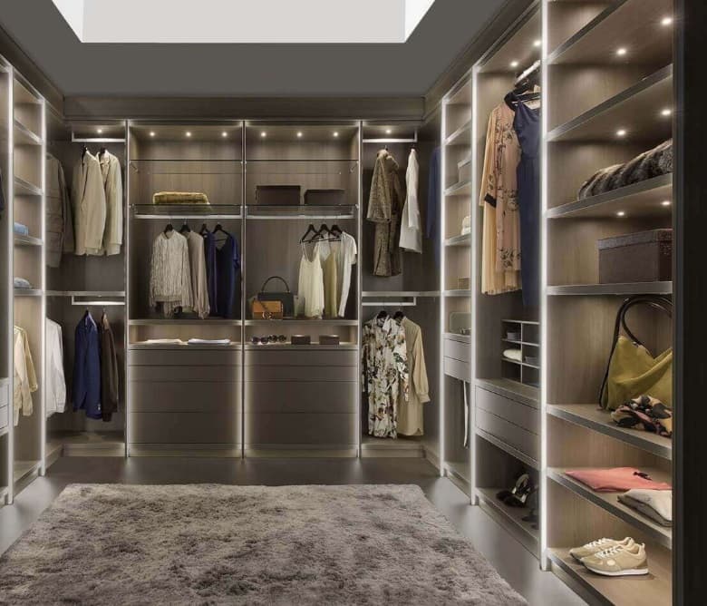 Dressing in grijs met ledverlichting in de open vakken, hangroedes en ruimte voor tassen