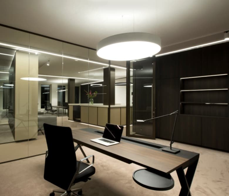 Directiekantoor met een maatwerk bureau in donker eiken, glazen wanden en een ronde plafondverlichting