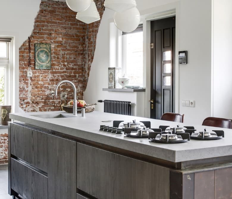 Landelijke keuken tegen een muur van oud metselwerk, met composiet werkblad en een ruim kookeiland