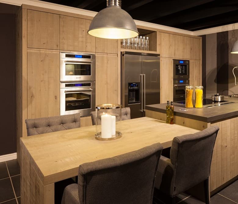 Eiken keuken met ingebouwde ovens en rvs koelkast, met een aangeschoven eettafel en donkere stoelen