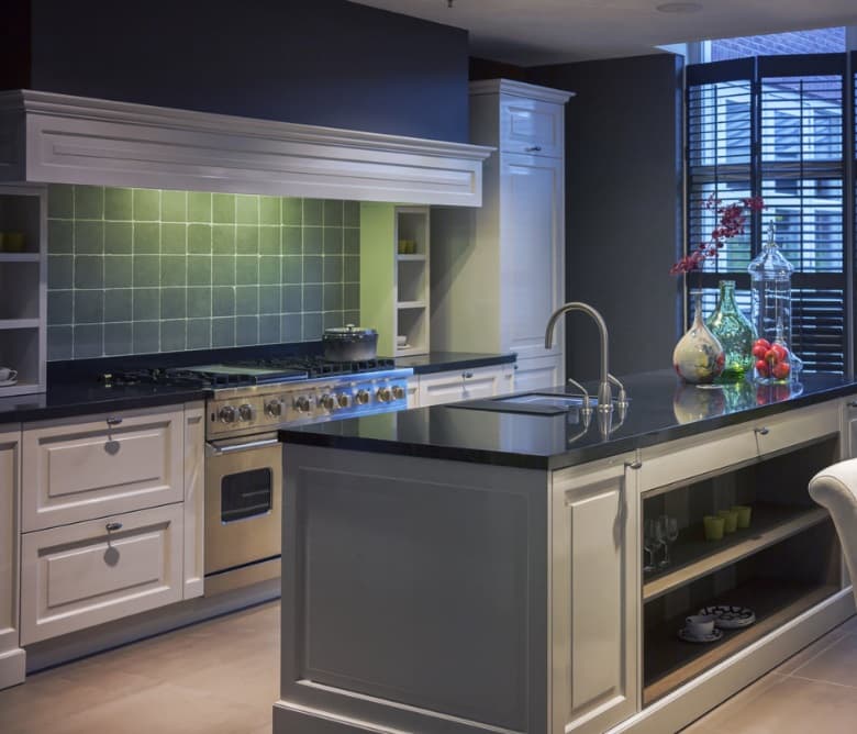 Klassieke keuken met groene wandtegels achter het fornuis, donker werkblad en een kookeiland in taupe