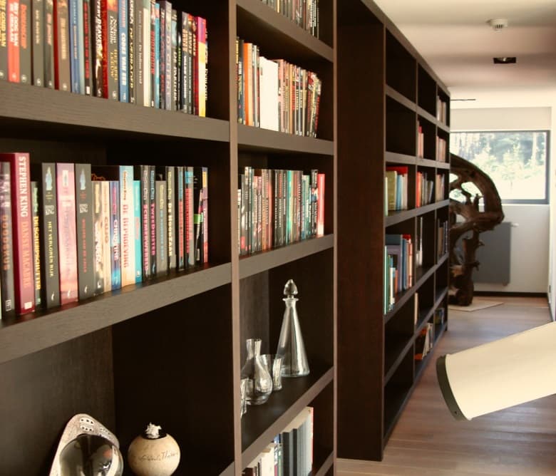 Donkerbruine boekenkast op maat over de volle hoogte, met open vakken rond een doorgang