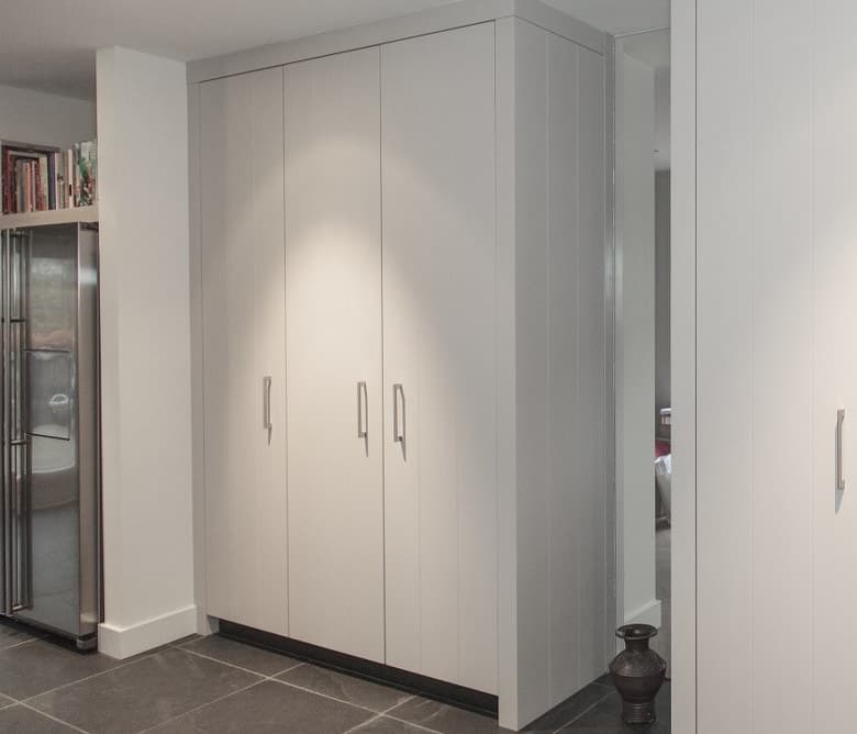 Gelakte witte kastwand op maat met hoge deuren, naast de koelkast